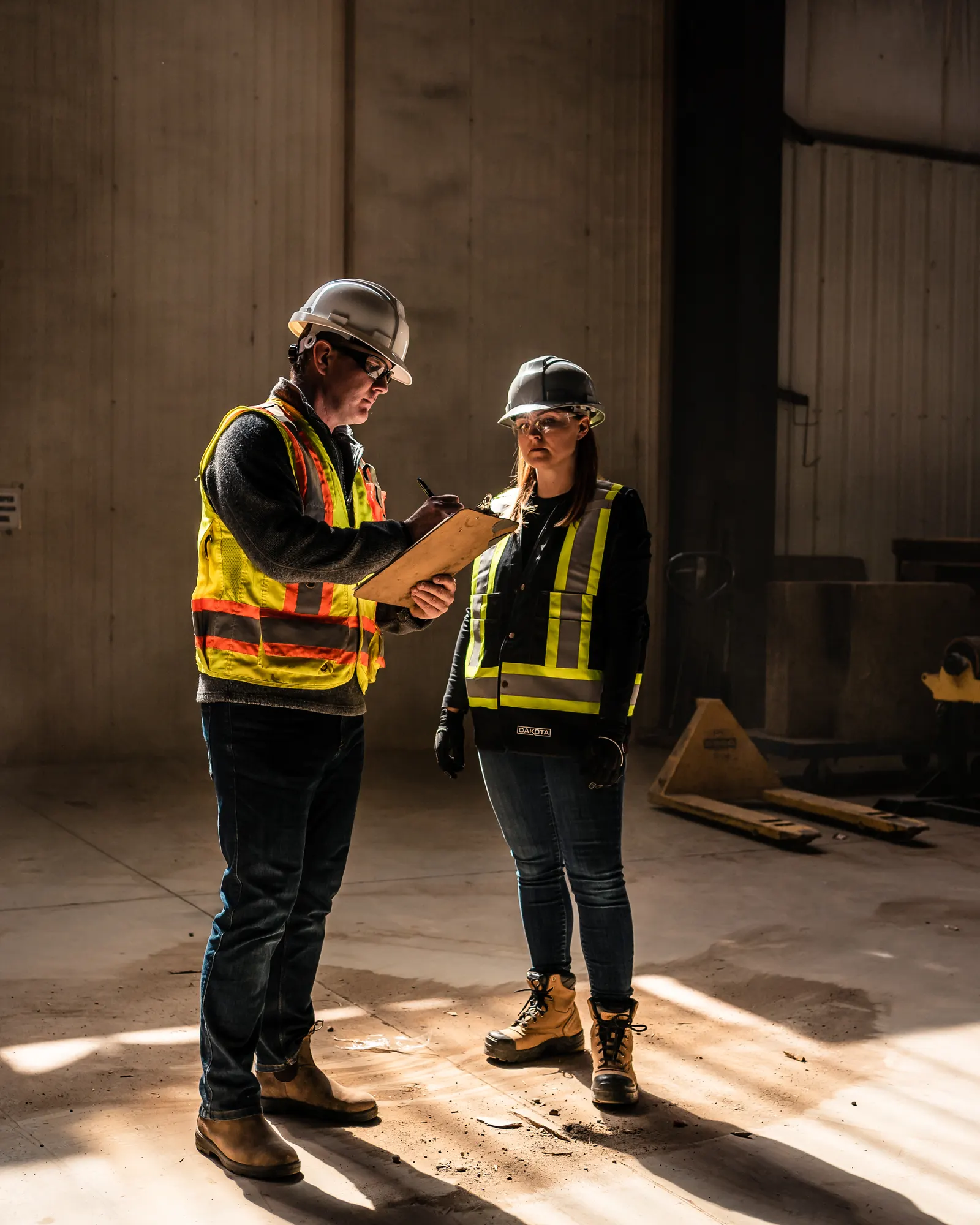 A foreman completing a digital safety form on a tablet at a Canadian worksite.